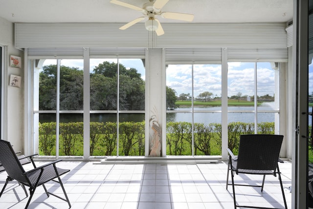 unfurnished sunroom featuring ceiling fan and a water view