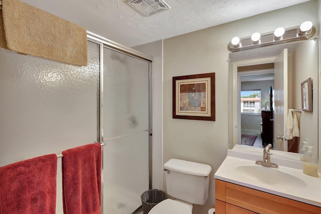 bathroom featuring a textured ceiling, vanity, toilet, and walk in shower