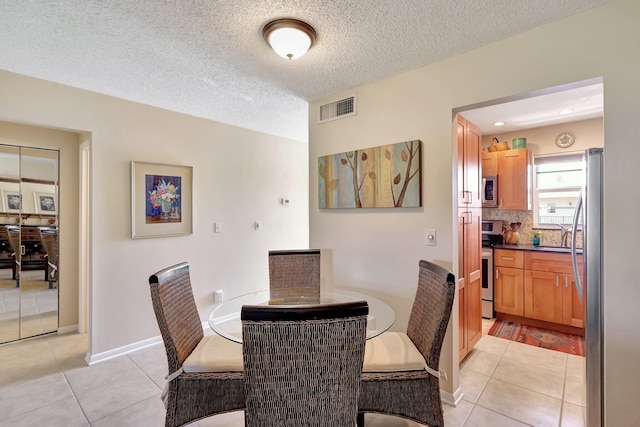 dining space featuring light tile patterned floors and a textured ceiling