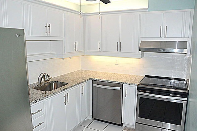 kitchen with white cabinets, appliances with stainless steel finishes, wall chimney exhaust hood, and light stone countertops