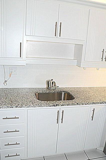 kitchen with white cabinets, light stone countertops, tasteful backsplash, and sink