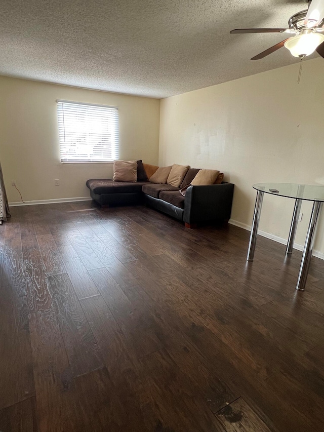 unfurnished living room featuring a textured ceiling, ceiling fan, and dark wood-type flooring