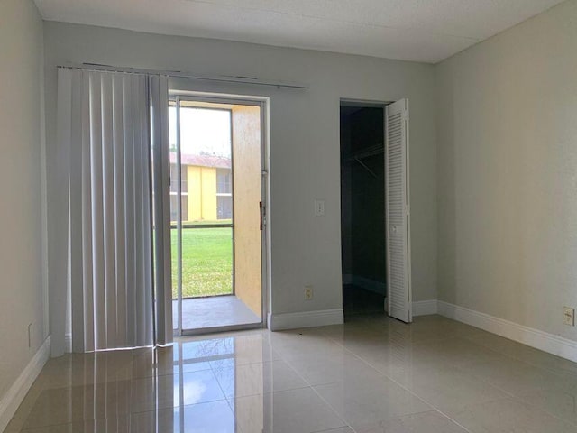 unfurnished room featuring plenty of natural light and light tile floors