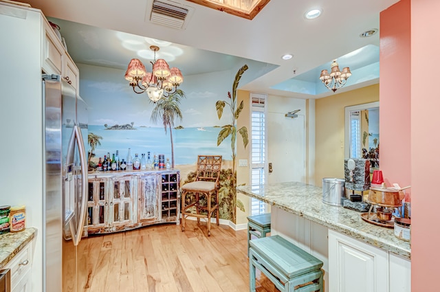 bar featuring white cabinetry, stainless steel fridge, light wood-type flooring, and an inviting chandelier