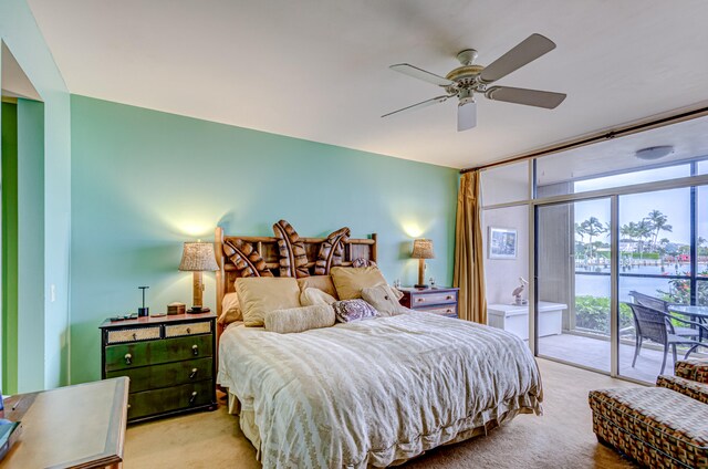 bedroom with access to outside, expansive windows, ceiling fan, and light colored carpet