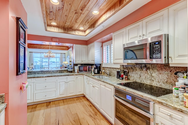 kitchen featuring a tray ceiling, sink, white cabinets, and appliances with stainless steel finishes