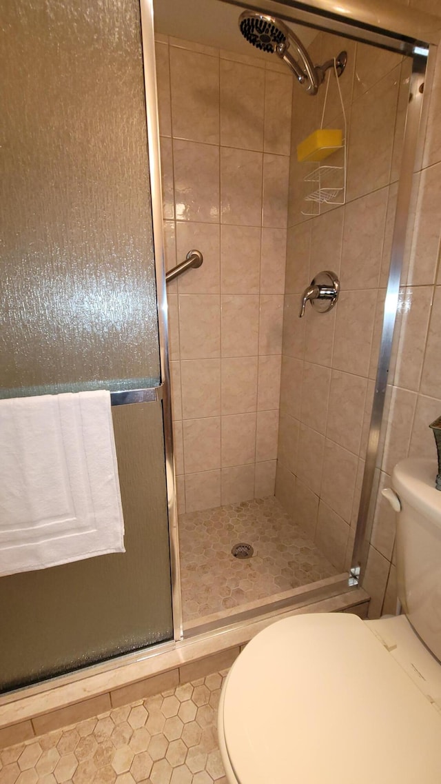 bathroom with a shower with door, tile floors, and toilet