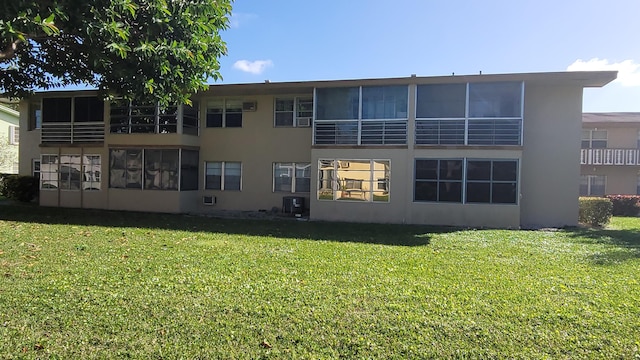 back of house with central AC unit and a yard