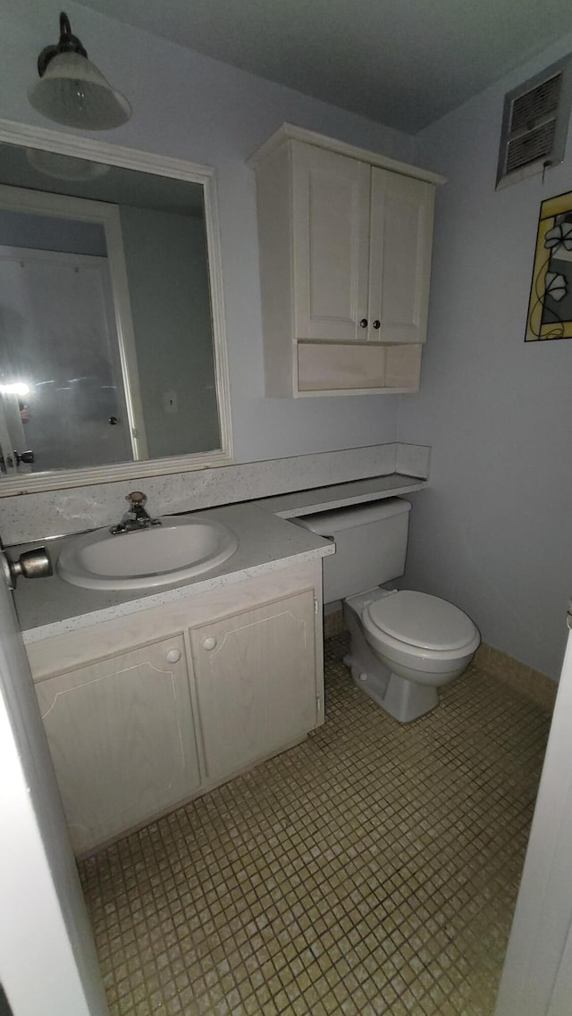 bathroom with toilet, tile floors, and vanity