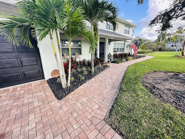 view of front of home featuring a garage, a front lawn, a porch, and stucco siding