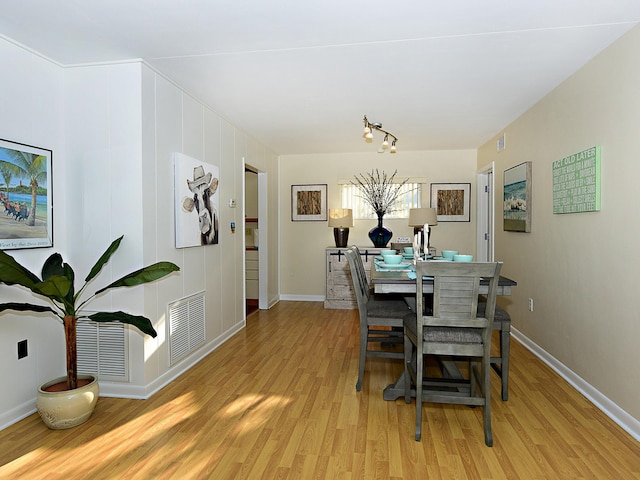 dining area with light hardwood / wood-style floors and track lighting