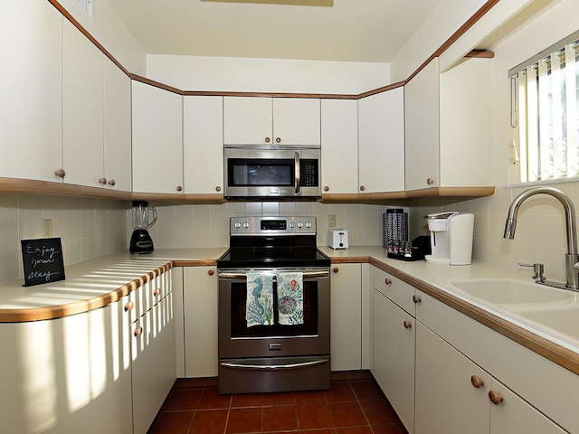 kitchen with appliances with stainless steel finishes, white cabinetry, and tasteful backsplash