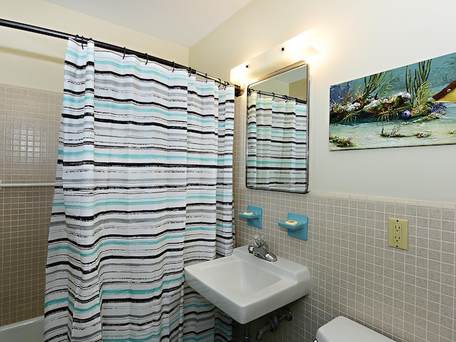 bathroom with tile walls, backsplash, sink, and toilet