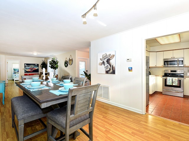 tiled dining area featuring rail lighting