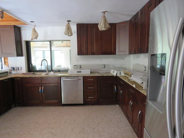 kitchen featuring sink, light tile patterned floors, decorative light fixtures, light stone counters, and stainless steel appliances