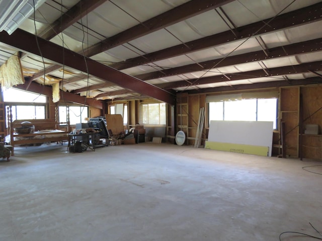 misc room featuring beam ceiling, a wealth of natural light, and concrete flooring