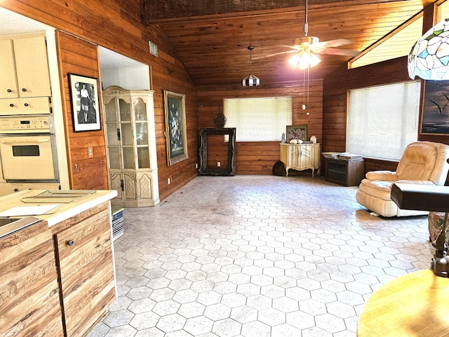 interior space featuring wooden walls, wooden ceiling, ceiling fan, and lofted ceiling