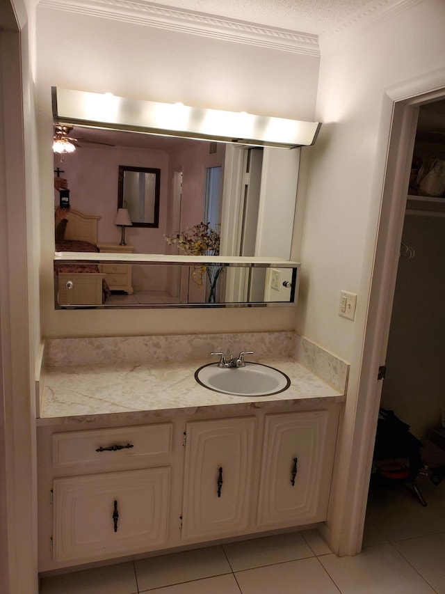 bathroom with vanity with extensive cabinet space, tile flooring, ornamental molding, and a textured ceiling