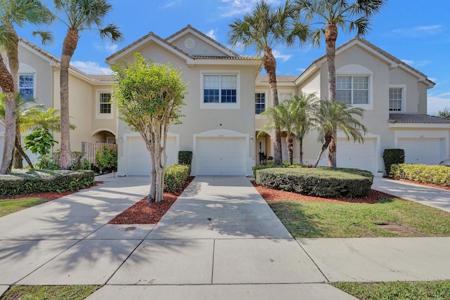 view of front of property featuring driveway, an attached garage, a tile roof, and stucco siding