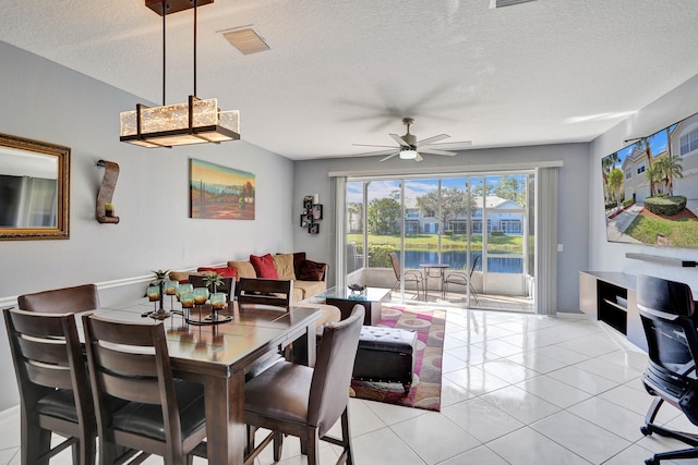 dining room featuring light tile patterned floors, a textured ceiling, visible vents, and a ceiling fan