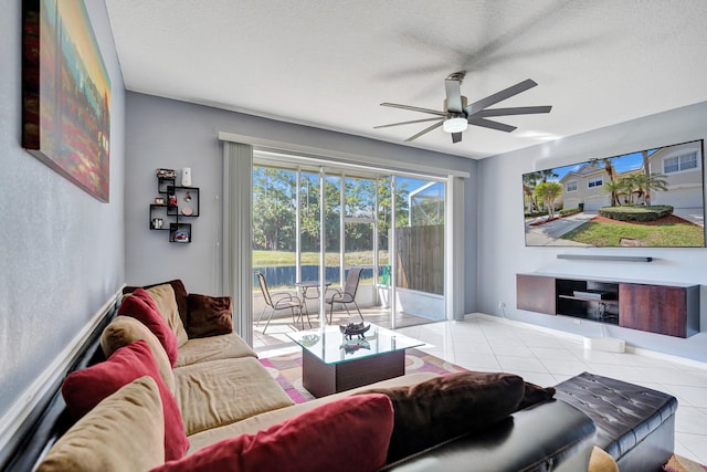 living area featuring tile patterned flooring, a textured ceiling, baseboards, and a ceiling fan