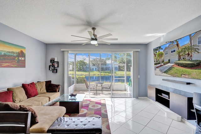 living room with ceiling fan, a textured ceiling, baseboards, and light tile patterned floors