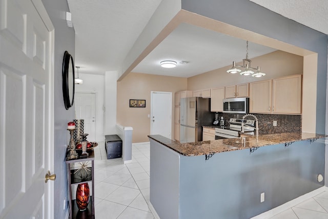 kitchen featuring light tile patterned floors, a peninsula, appliances with stainless steel finishes, and backsplash