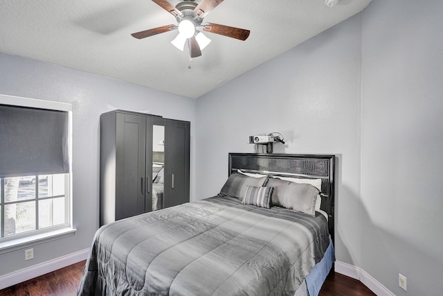 bedroom with vaulted ceiling, a textured ceiling, ceiling fan, and dark hardwood / wood-style flooring