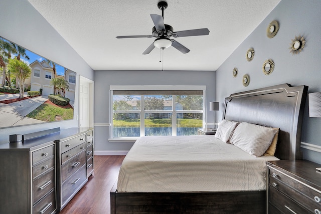 bedroom featuring baseboards, ceiling fan, dark wood-style flooring, vaulted ceiling, and a textured ceiling