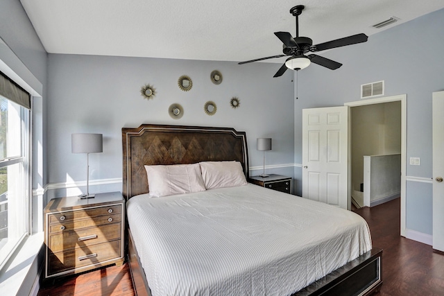 bedroom with a ceiling fan, wood finished floors, visible vents, and baseboards