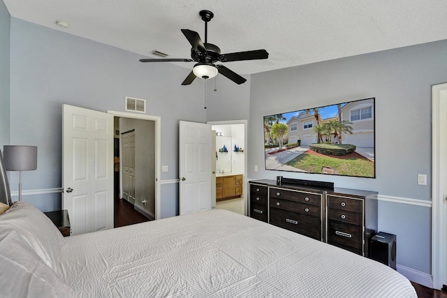 bedroom featuring ensuite bath, baseboards, visible vents, and a ceiling fan