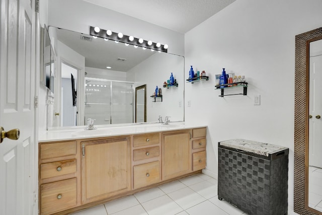 bathroom featuring a shower with door, vanity, and tile patterned floors