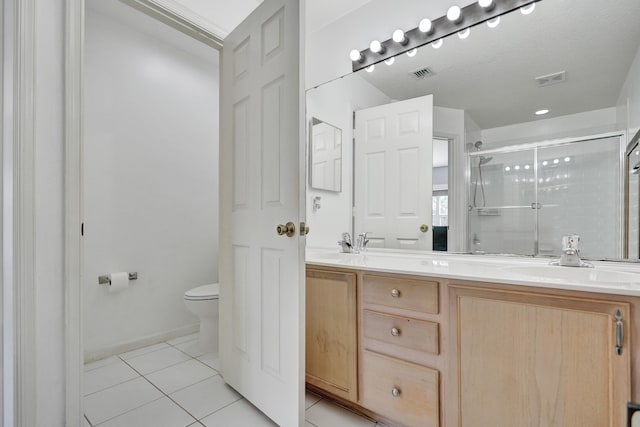 bathroom featuring tile patterned flooring, vanity, a shower with shower door, and toilet