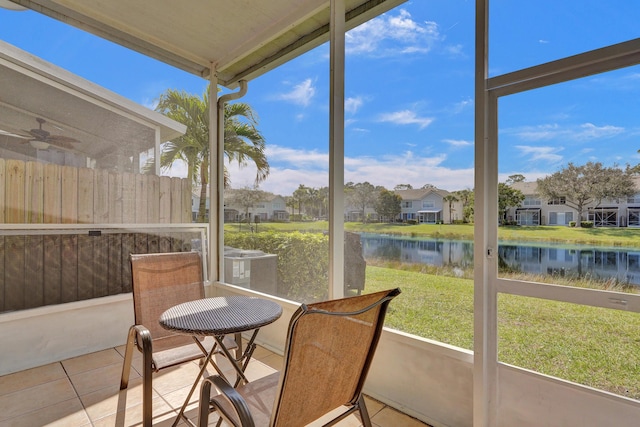 sunroom with a water view, a residential view, and a ceiling fan