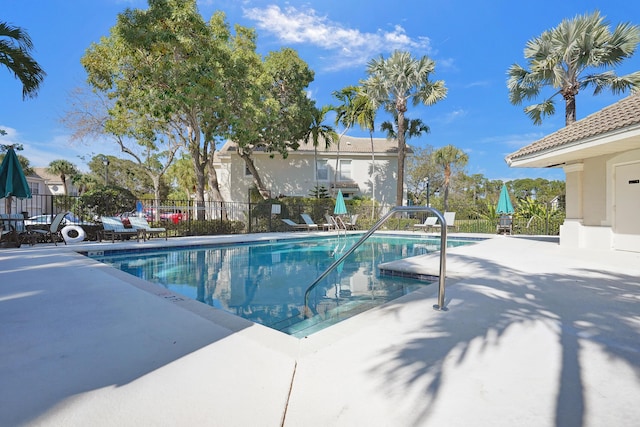 community pool with fence and a patio