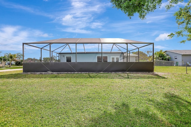 rear view of property featuring a yard and glass enclosure