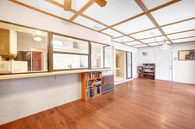 interior space featuring coffered ceiling, a notable chandelier, and light wood-type flooring