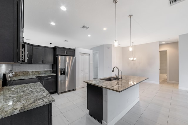 kitchen featuring stainless steel fridge with ice dispenser, sink, an island with sink, and pendant lighting