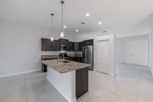 kitchen featuring a center island with sink, sink, tasteful backsplash, light stone counters, and stainless steel appliances