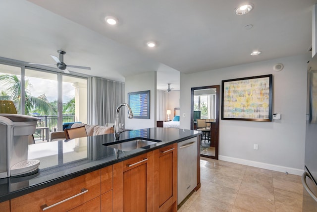 kitchen with stainless steel dishwasher, ceiling fan, dark stone counters, and sink