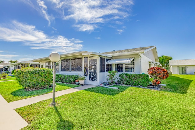 single story home with a front yard and a sunroom