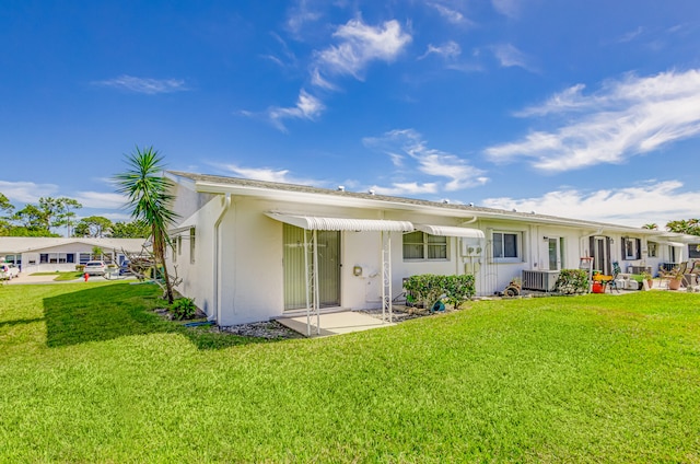 rear view of property with a yard and central air condition unit