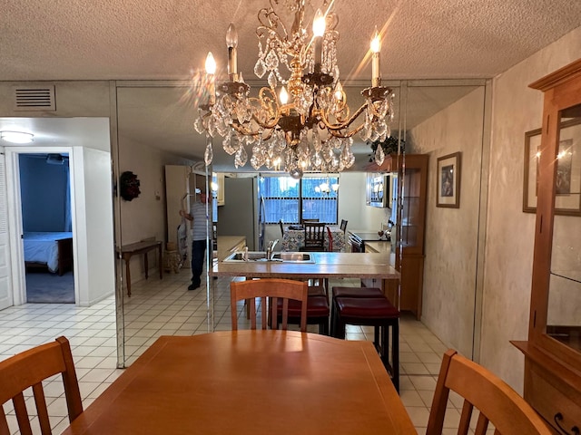 tiled dining room with sink, a textured ceiling, and an inviting chandelier