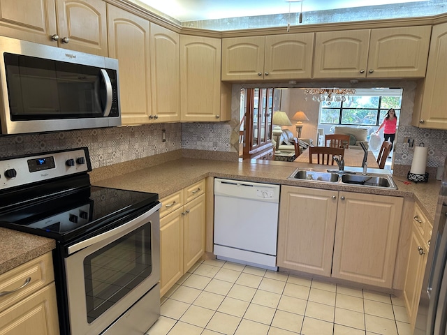 kitchen featuring stainless steel appliances, light tile flooring, light brown cabinetry, backsplash, and sink