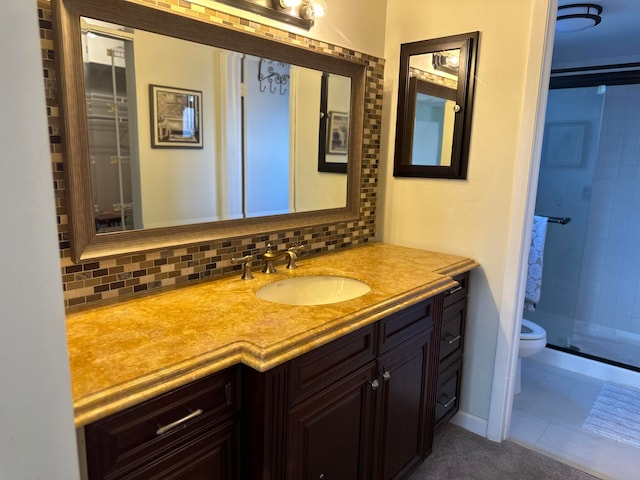 bathroom featuring toilet, a shower with door, tile flooring, tasteful backsplash, and vanity