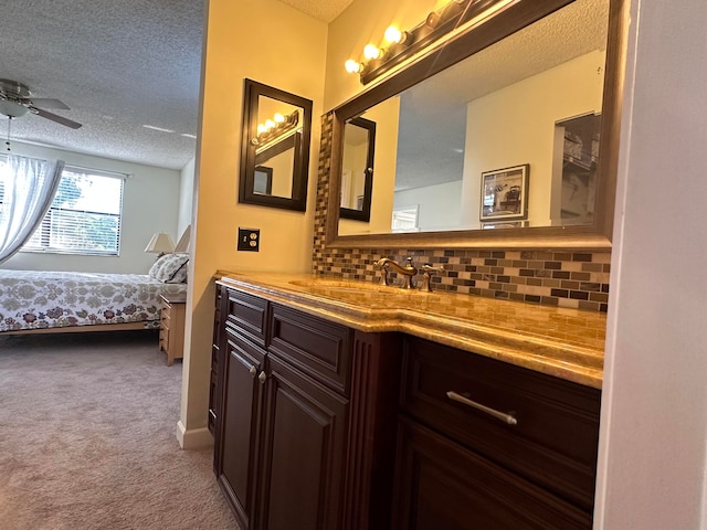 bathroom featuring a textured ceiling, tasteful backsplash, ceiling fan, and vanity