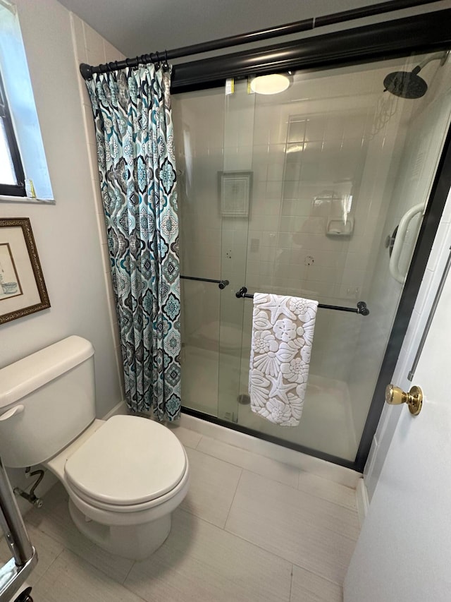 bathroom with tile flooring, a shower with shower curtain, and toilet