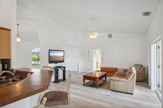 living room with high vaulted ceiling, ceiling fan, sink, and light wood-type flooring