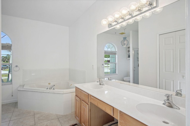 bathroom featuring toilet, large vanity, dual sinks, tile floors, and tiled tub