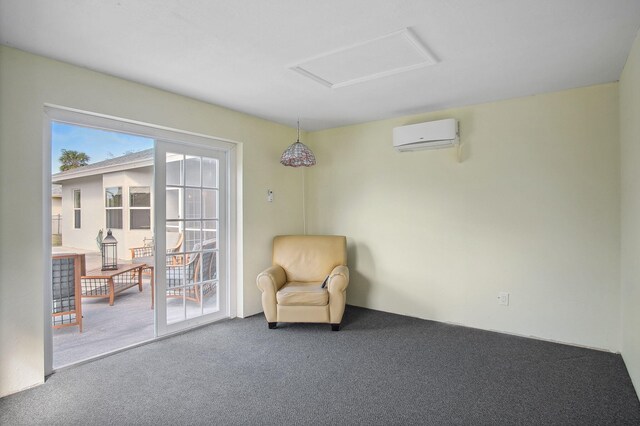 sitting room featuring dark colored carpet and an AC wall unit